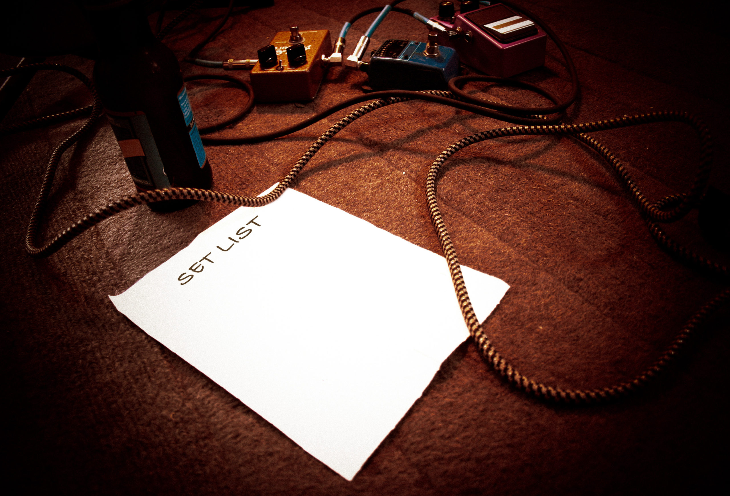 band setlist on stage with guitar effect pedals and cables